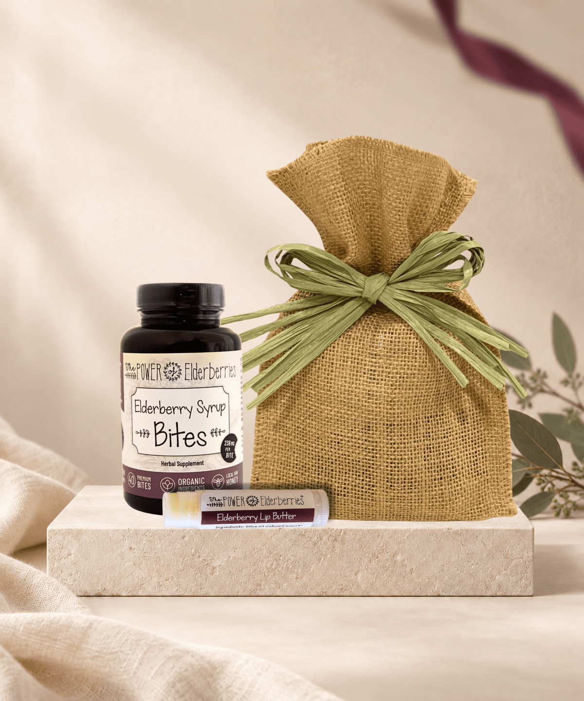 Wellness On-the-Go Gift Set with 40-count Elderberry Syrup Bites, Elderberry Lip Butter and a burlap bag with green raffia bow.