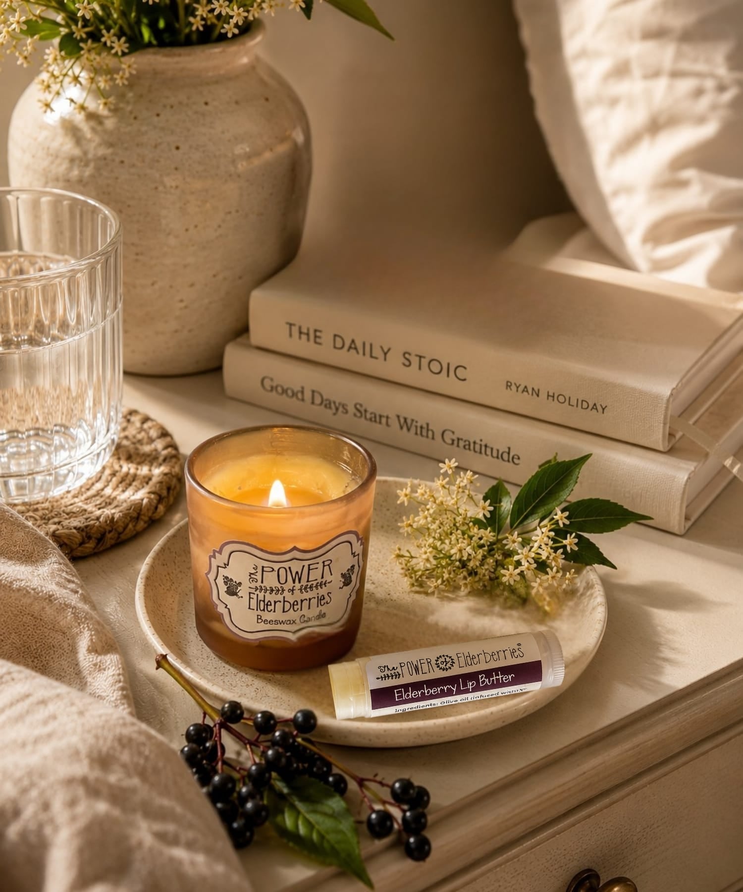Elderberry lip butter resting on a night stand next to an elderberry beeswax candle for an evening ritual.