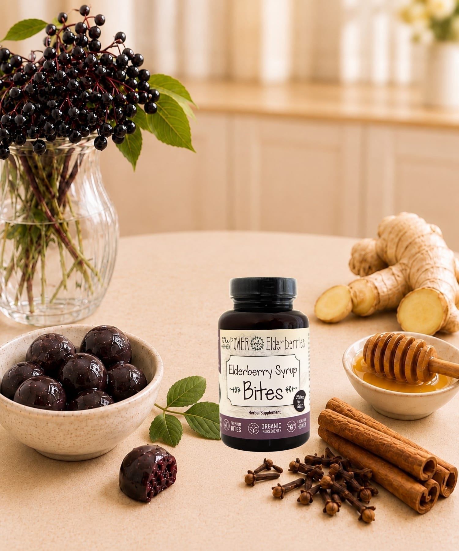 Elderberry syrup bites bottle styled with elderberries, raw honey, ginger root, cinnamon sticks, and cloves on a warm countertop.