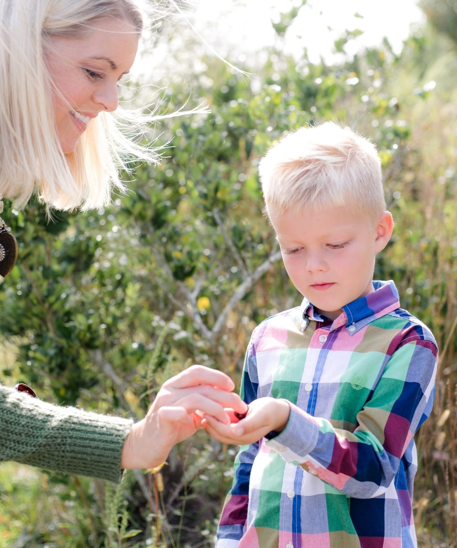 A mother giving her young son an elderberry syrup bite in the palm of his hand.