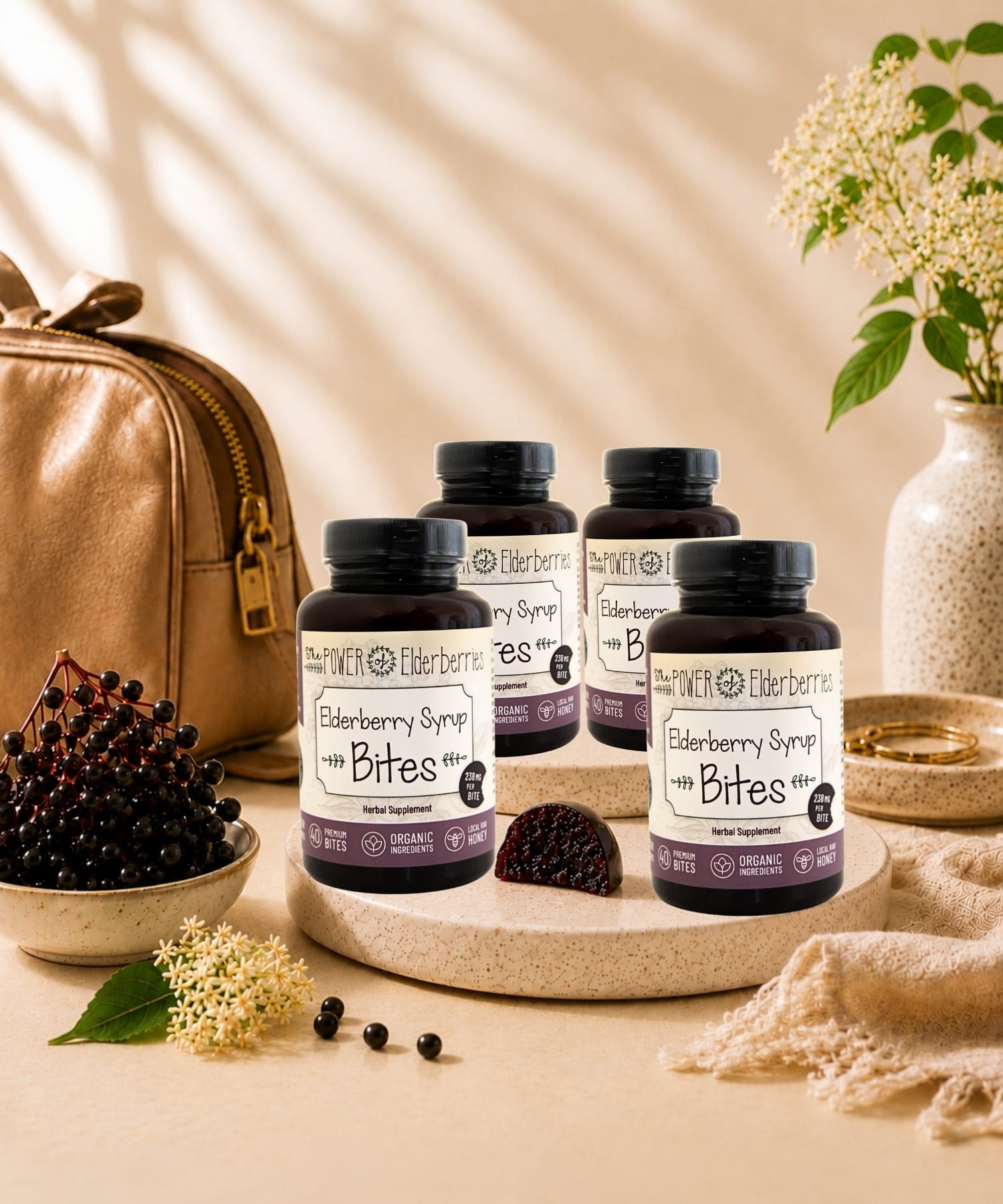 Four bottles of The POWER of Elderberries® Elderberry Syrup Bites styled with elderberries, ginger root, and local raw honey in a premium wellness setting.