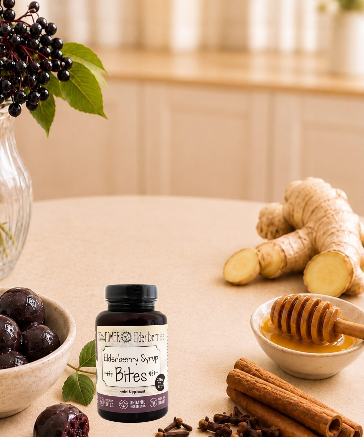 Elderberry syrup bites bottle styled with elderberries, raw honey, ginger root, cinnamon sticks, and cloves on a warm countertop.