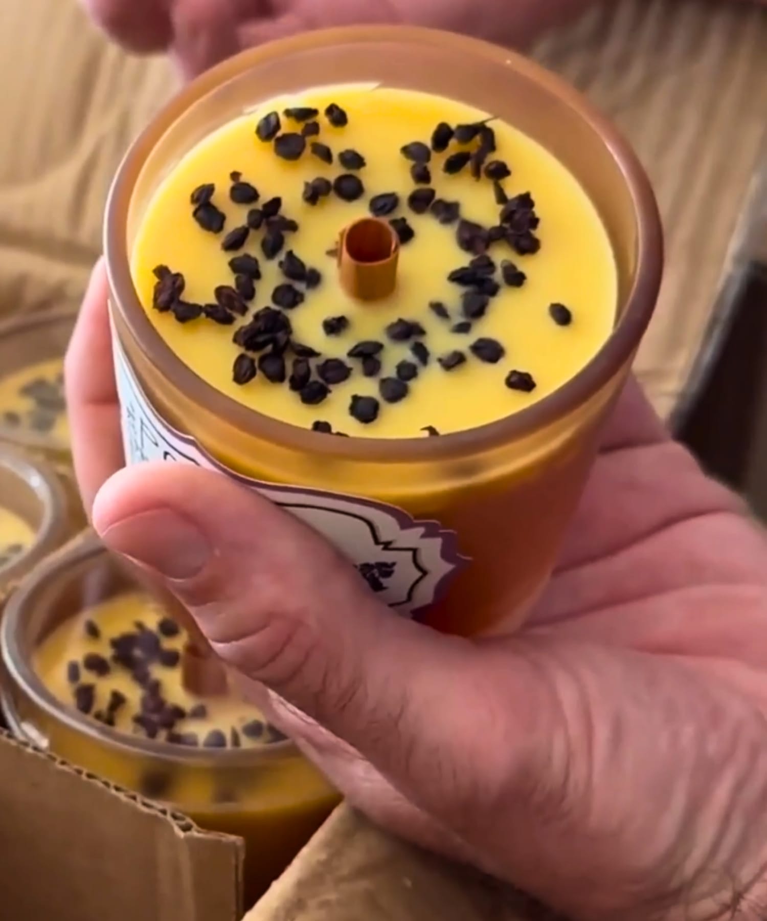 Handcrafted Signature Elderberry Beeswax Candle with wooden wick held by hand showing artisanal detail.